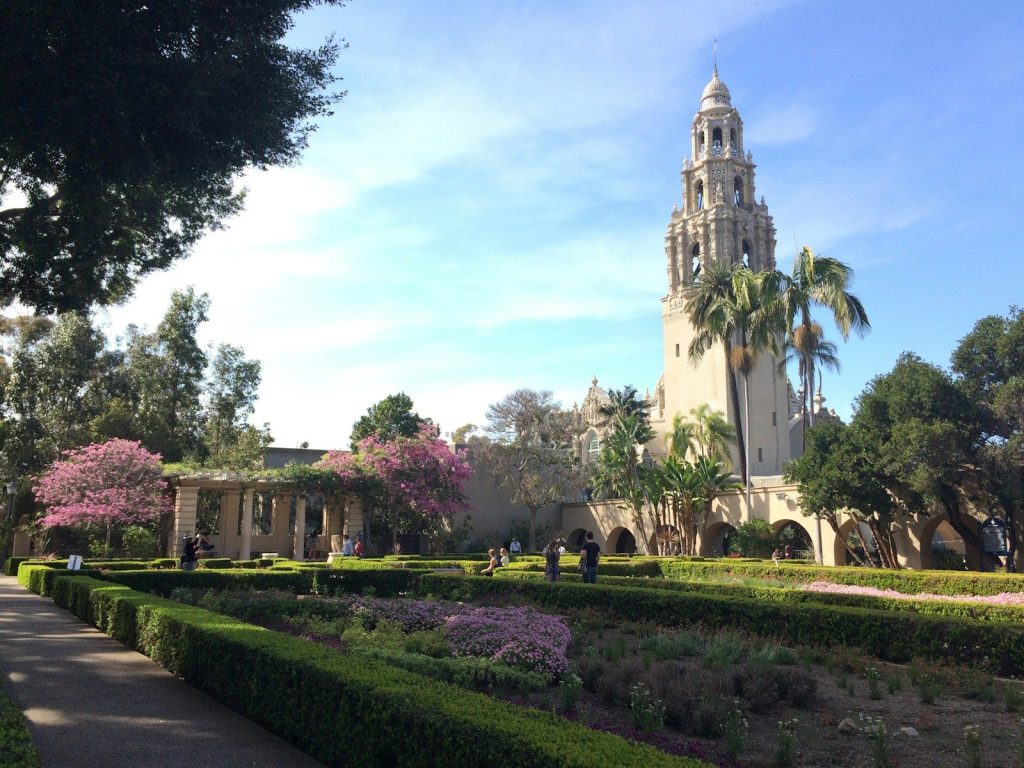 green grass and trees near white concrete building during daytime in Balboa park in San Diego, california
