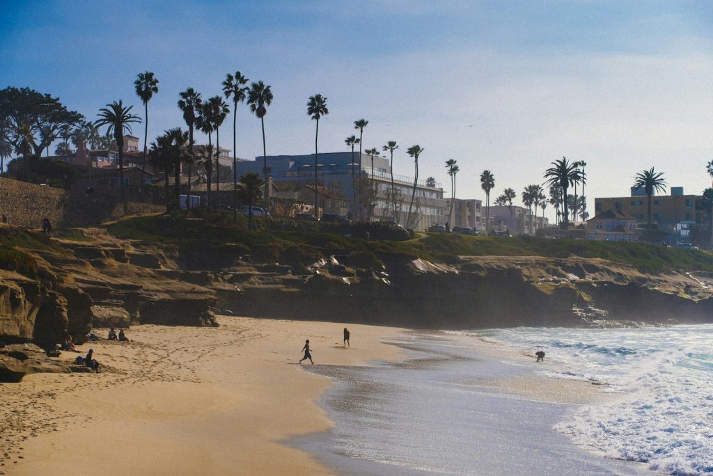 a couple of people walking along a beach next to the ocean San Diego la Jolla ca. planning guide for taking a trip to San diego